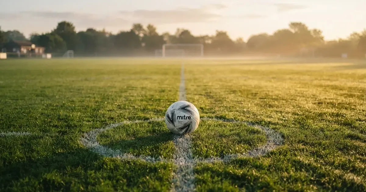 A ball on the centre spot of a grass pitch in morning light